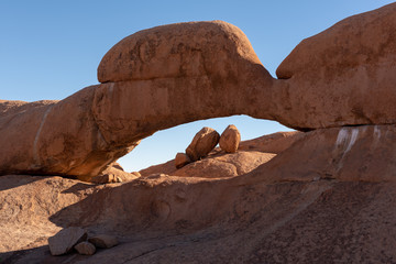 Massive boulder rock arch with smaller rocks gathered on a pile, Spitzkoppe, Namibia