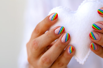 White felted heart in femaile hands with rainbow manicure. Love, valentine, lgbt, pride concept
