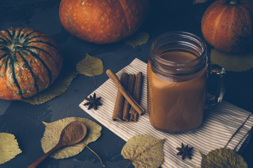 Pumpkin spice chai (masala tea). Autumn, fall or winter hot drink. Background with yellow leaves