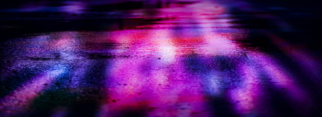 Light and shadows of the night city. Wet asphalt with neon. Soft image of the focus of the street...