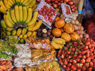 Different kind and mix of many fresh tropical fruits and berries lying on market stall. Beautiful display of exotic fruits at a local market in Indonesia. Assortment at a street market.