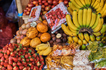 Different kind and mix of many fresh tropical fruits and berries lying on market stall. Beautiful display of exotic fruits at a local market in Indonesia. Assortment at a street market.