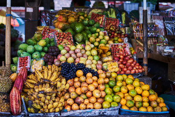 Different kind and mix of many fresh tropical fruits and berries lying on market stall. Beautiful display of exotic fruits at a local market in Indonesia. Assortment at a street market.