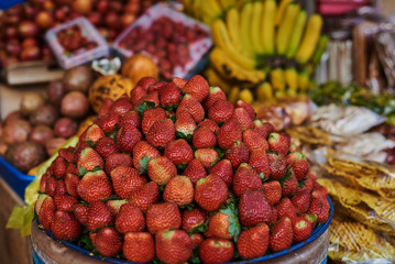 Different kind and mix of many fresh tropical fruits and berries lying on market stall. Beautiful display of exotic fruits at a local market in Indonesia. Assortment at a street market.