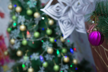 New Year's ball on a Christmas tree . A Christmas ball hangs on a Christmas tree branch. New Year and festive decoration. A Christmas ball hangs on the background of a clock. It's time for a new year