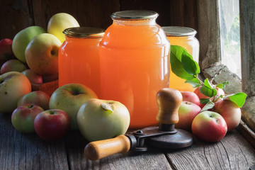 Glass jars of apple juice, apple fruits and can lid closing machine for canning.