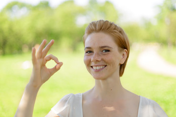 Young beautiful girl student outdoors at street walking in park at a sunny day wearing smart casual simple and modest outfit showing thumbs up