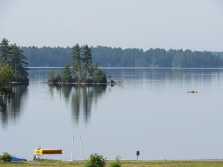 View across a field of Damariscotta Lake in Maine with a person kayaking in the distance 