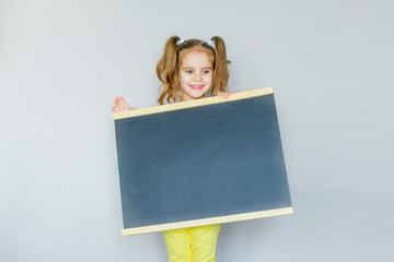 back to school. funny little girl from elementary school holding a Board. education. place for your text. selective focus. concept of education.	