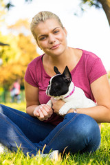 Smiling young woman playing with puppy. Her best friend