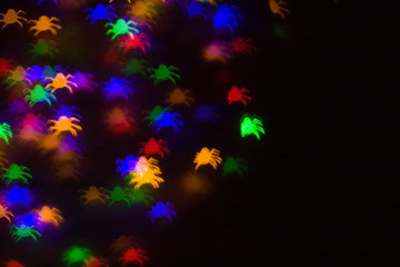 holidays, decoration and party concept - defocused bokeh multicolor lights in shape of spiders for...