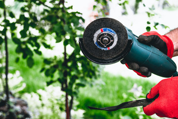 The man is sharpening the mower's knife with a grinder. Using an angle grinder for sharpening,...