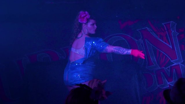 Curvy burlesque dancer slowly strips off her dress and teases the audience during a sexy live performance