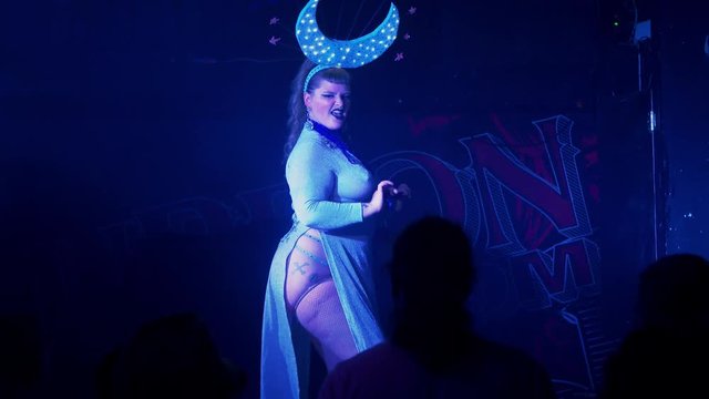 Costumed curvy burlesque dancer dances suggestively and teases the audience