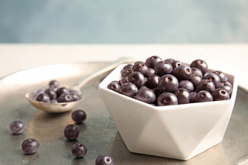 Bowl with fresh acai berries on tray, closeup
