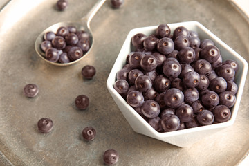 Bowl with fresh acai berries on tray, closeup
