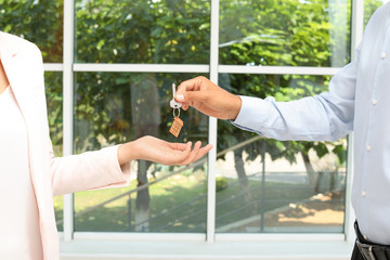Real estate agent giving key to woman on blurred background