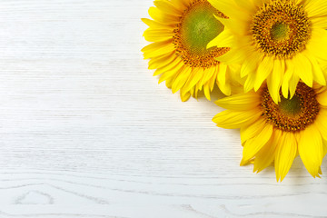Fototapeta premium Yellow sunflowers on wooden background, top view