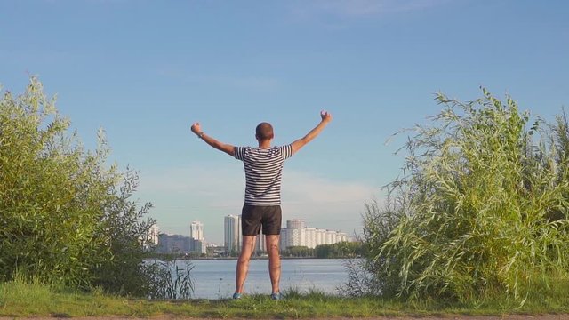 man with a cup in his hands rejoices in sports victory. Dances and jumps on evening city. Slow motion