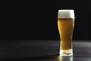 Glass with cold tasty beer on dark background