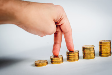 The man's hand fingers climb the stairs made of gold coins. Financial growth concept.