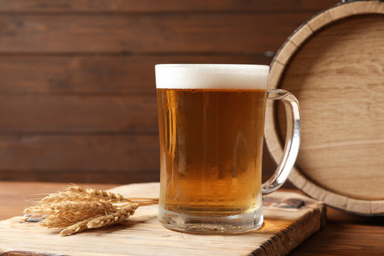 Glass mug with cold tasty beer and malt on wooden table