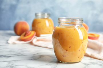 Tasty peach smoothie in glass jars on table