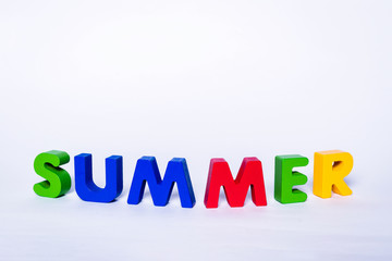 Fototapeta premium Inscription summer with colorful letters isolated. The word SUMMER is made of wooden letters in various colors. The concept of holidays and the upcoming break from school.