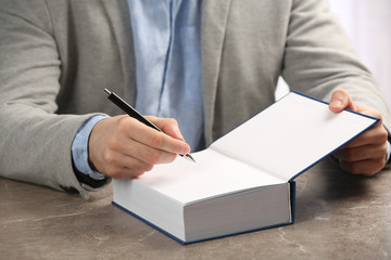 Writer signing autograph in book at table, closeup