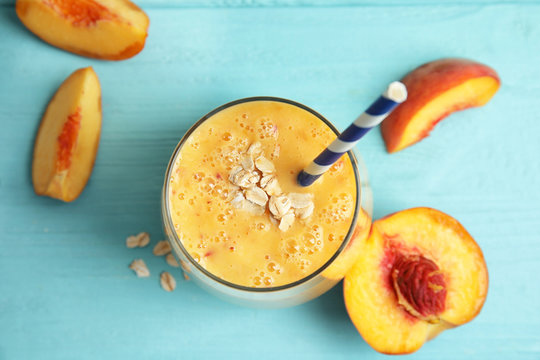 Tasty peach smoothie in glass and fresh fruit on wooden background, top view