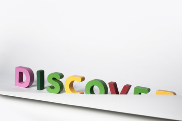 DISCOVER word made of colorful letters. Partially covered DISCOVER sign made of wooden letters. The concept of discovering new things, traveling and learning about new places.