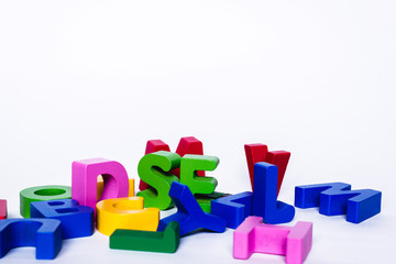 Scattered various colorful and wooden letters on a white background.