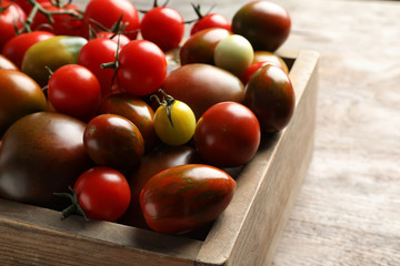 Crate with tasty juicy tomatoes on table, closeup