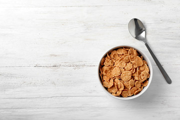 Bowl of cornflakes on light table, top view with space for text. Whole grain cereal for breakfast