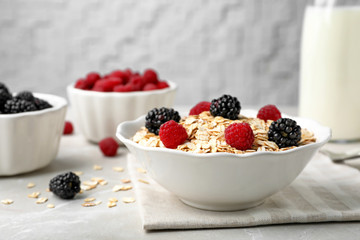 Fototapeta na wymiar Bowl with rolled oat and berries on light table. Whole grain cereal for breakfast