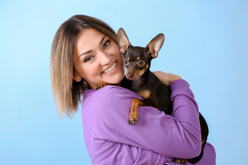 Young beautiful smiling woman with cute dog on color background