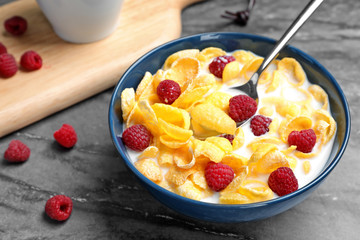Bowl with cornflakes and milk on dark table. Whole grain cereal for breakfast