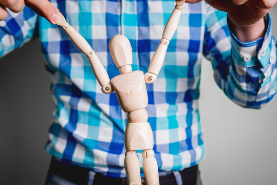The man is holding a wooden mannequin. Control and control of the manikin, other people. Business concept, coaching and human manipulation. Controlling other people. - Powered by Adobe