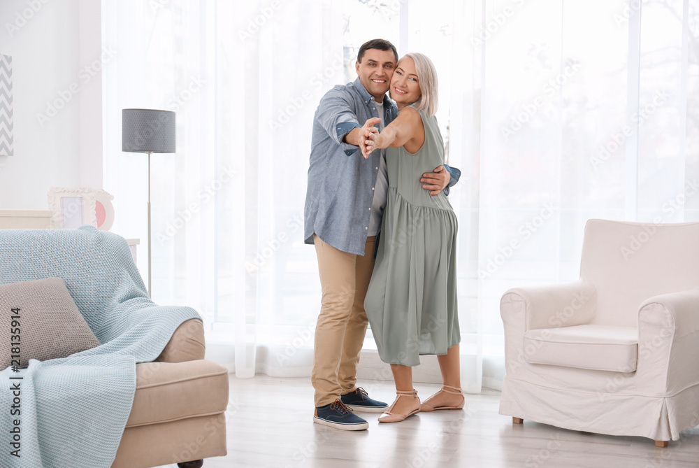 Poster adorable mature couple dancing together in living room