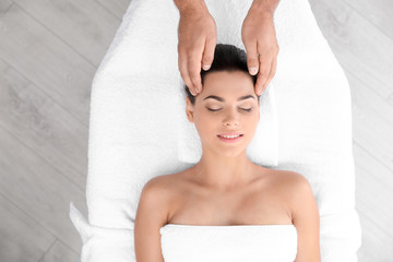 Relaxed woman receiving head massage in wellness center, top view