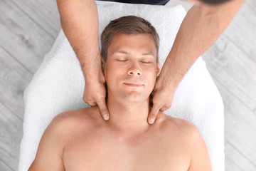 Relaxed man receiving head massage in wellness center, top view