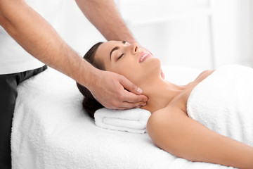 Fototapeta na wymiar Relaxed woman receiving neck massage in wellness center