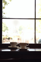 Cups of fresh aromatic coffee on table near window