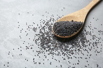 Spoon with poppy seeds on grey background