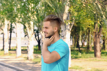 Fototapeta premium Young man checking pulse outdoors on sunny day