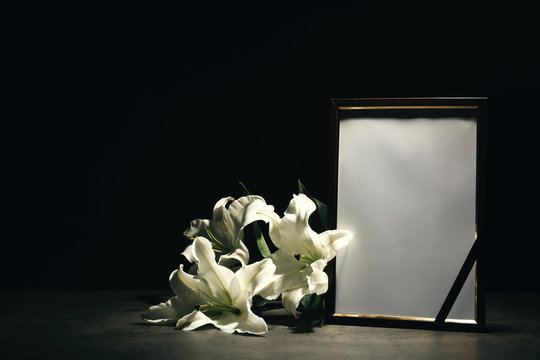 Funeral photo frame and lily flowers on dark background