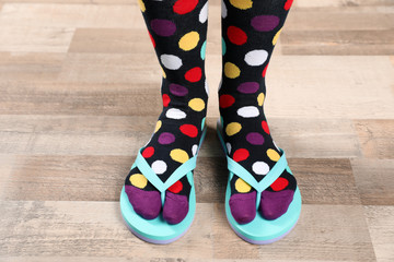 Woman wearing bright socks with flip-flops standing on floor
