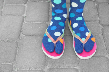 Woman wearing bright socks with flip-flops standing outdoors