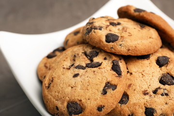 Plate with chocolate chip cookies on grey background, closeup