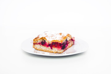 Tasty and fresh rhubarb cake. A piece of cake with red fruit on a white plate isolated on a light, white background. A treat on a plate. Sweet-sour dough.